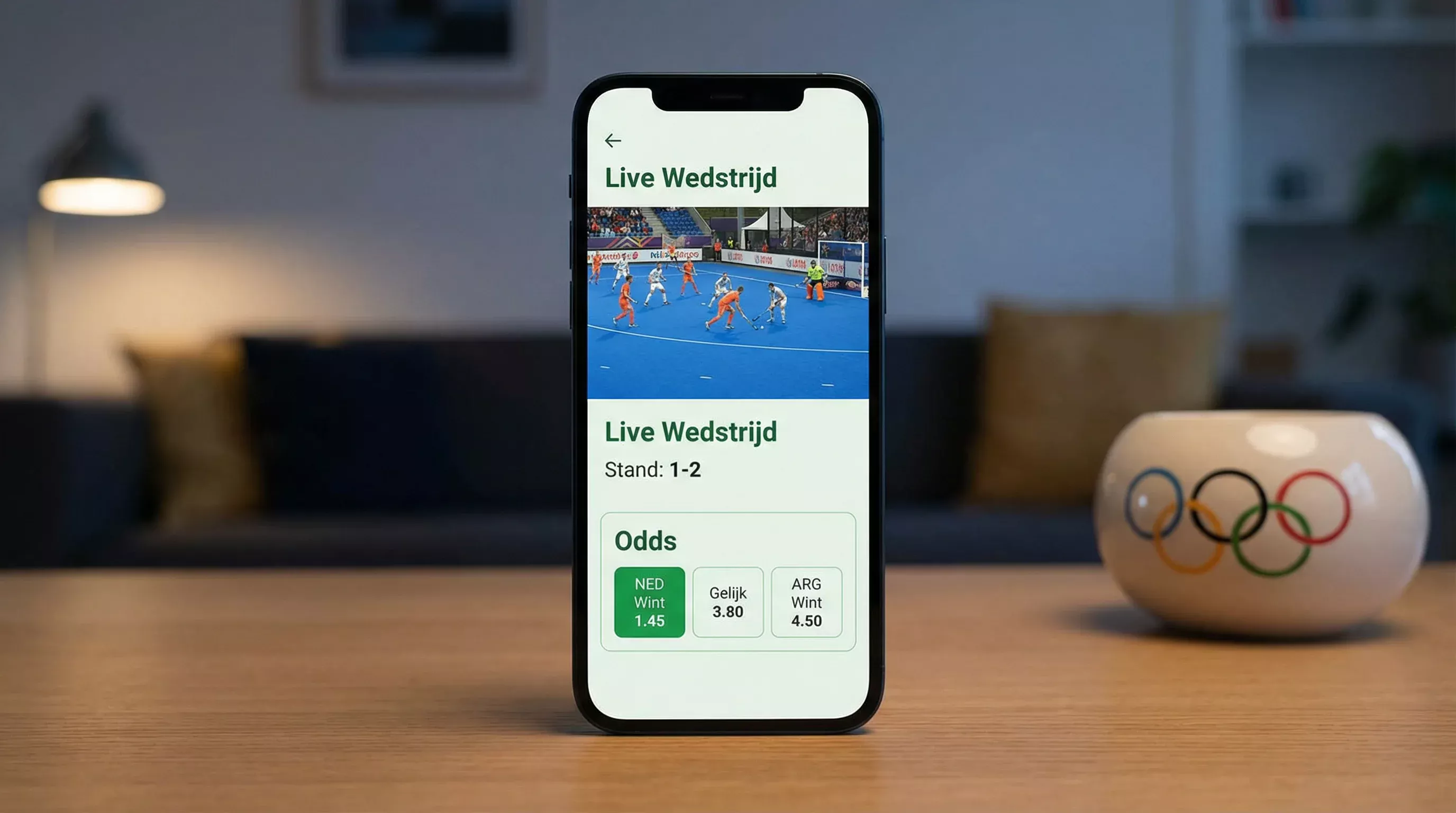 Smartphone met live hockeywedstrijd en wedopties naast olympische ringen